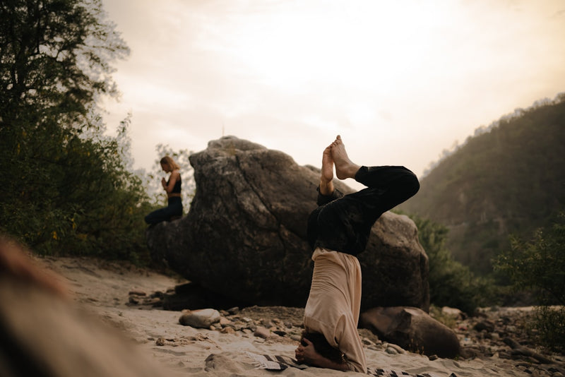 a woman doing a handstand on top of a rock