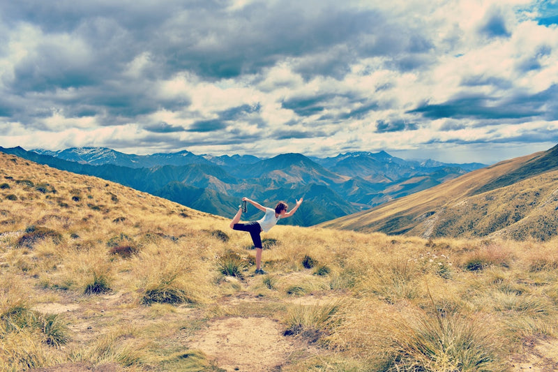 woman in white t-shirt doing yoga on hill