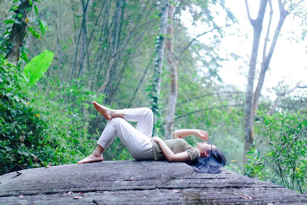 a woman laying on a log in the woods