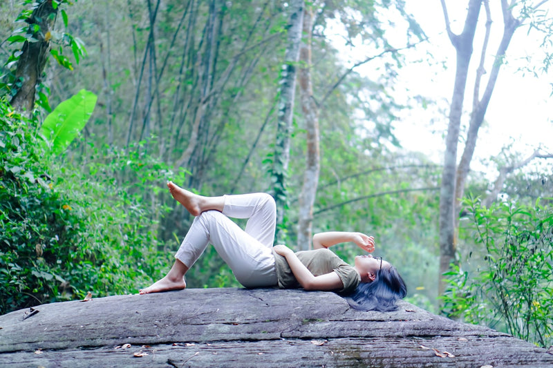 a woman laying on a log in the woods