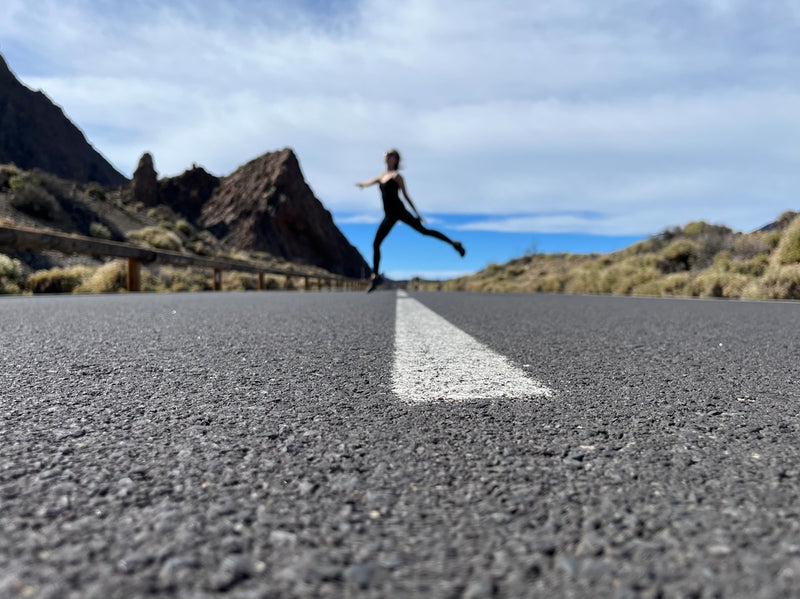 a woman is running down the road in the middle of nowhere