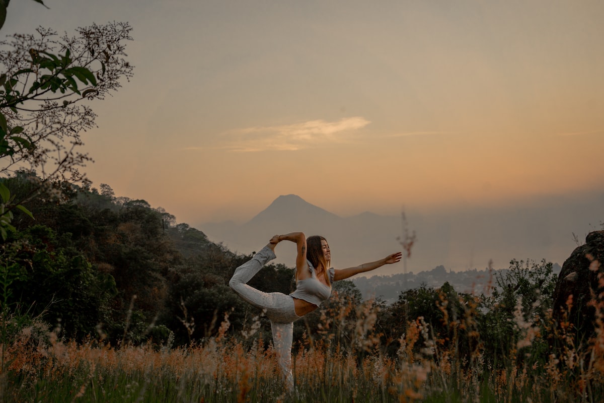a woman doing a yoga pose in a field