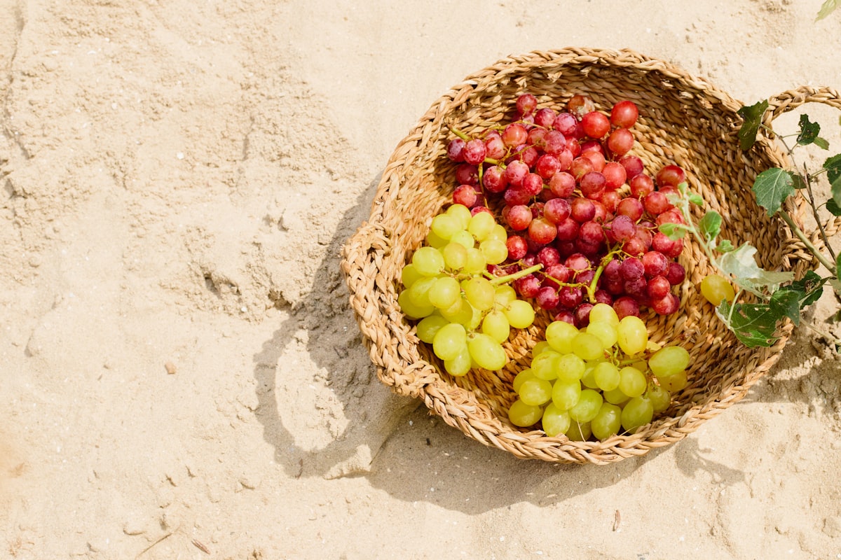 Grapes in a basket on the sand.